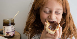 Young girl eating Datehini spread on bread